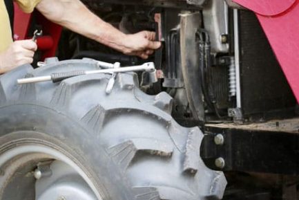 Man Repairs Large Red Tractor — Diesel Mechanic in Yandina, QLD